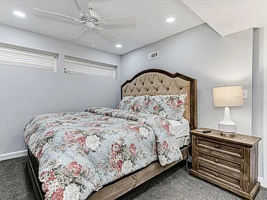 The second Azalea bedroom with a tufted headboard, floral bedding, and a round wall mirror