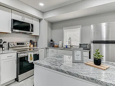 A second angle on the Azalea kitchen: white shaker cabinets, granite counters, and stainless appliances