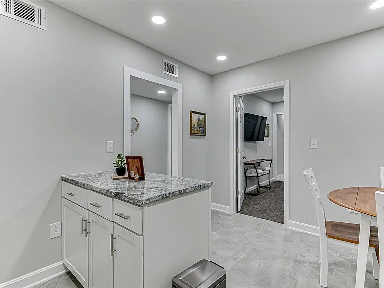 The Azalea's roomy eat-in kitchen with white cabinets, granite counters, and a breakfast table by the window