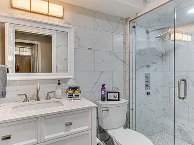 A second view of the Dogwood bath — white vanity, marble-look tile, and the shower enclosure