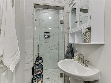 The shower bathroom in The Dogwood apartment with tiled walls and a glass door