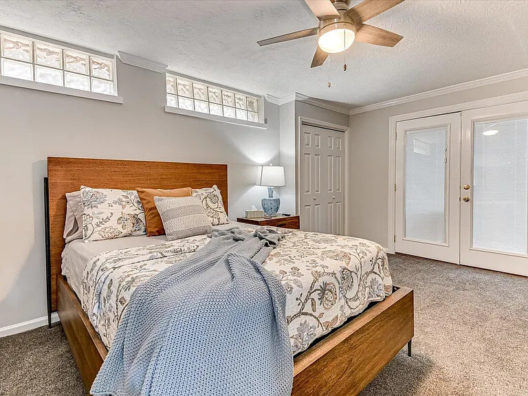 A Dogwood bedroom with a light timber bed, patterned bedding, and a dresser and mirror