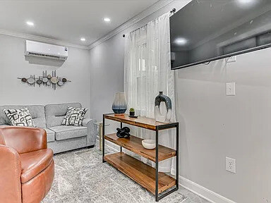 The Dogwood's cosy den with a grey sofa, leather swivel chair, and wall-mounted television