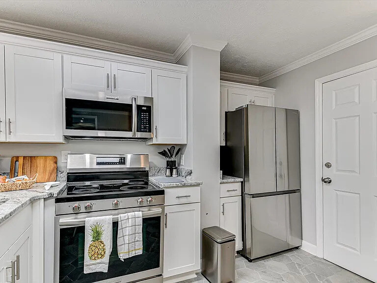 The Dogwood's compact eat-in kitchen with white cabinets, granite counters, and a window over the sink