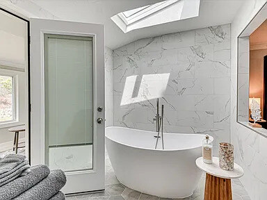 A second Magnolia bath with skylights, full marble tile walls, and a freestanding tub