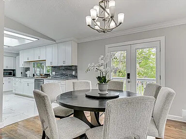 The Magnolia's dining table beside a floor-to-ceiling marble fireplace, with the kitchen beyond
