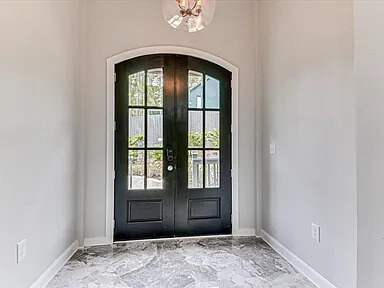 The Magnolia's arched entry hall with a stone-tiled floor, lantern chandelier, and round console table