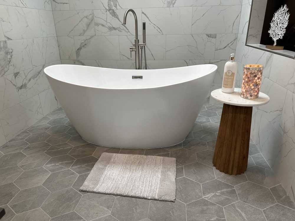 The master bath's separate soaking tub — a freestanding oval tub against marble tile