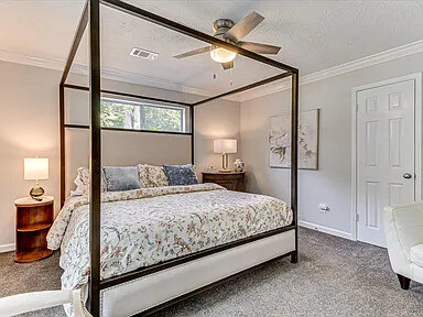 The Magnolia's master bedroom with a black four-poster bed, chaise longue, and windows on two walls