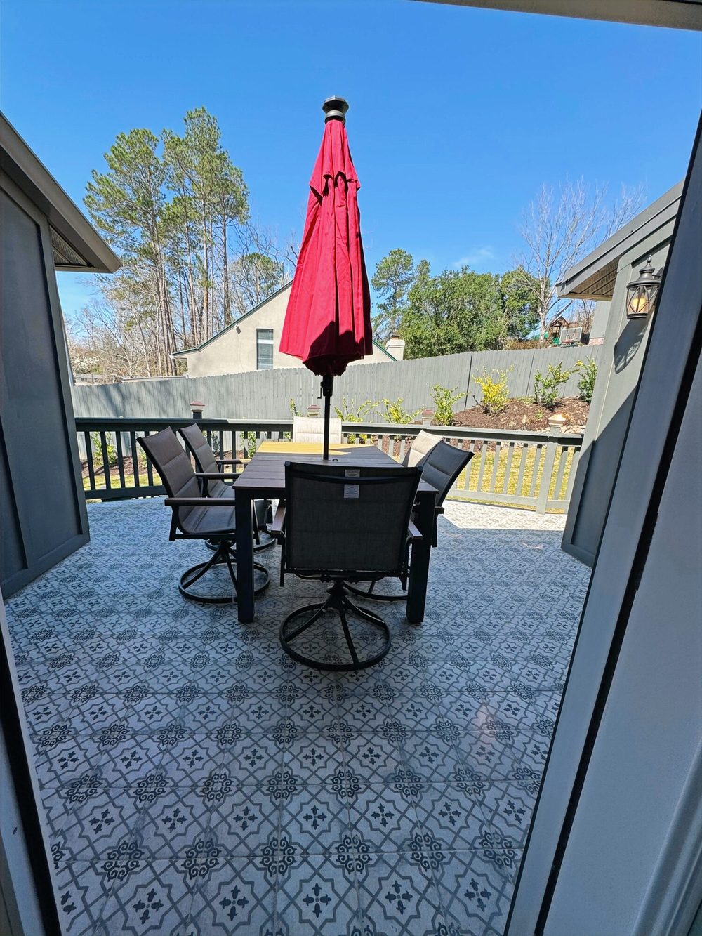 The Magnolia’s tile patio: patterned tile underfoot, a table and four chairs, and a red umbrella facing the yard