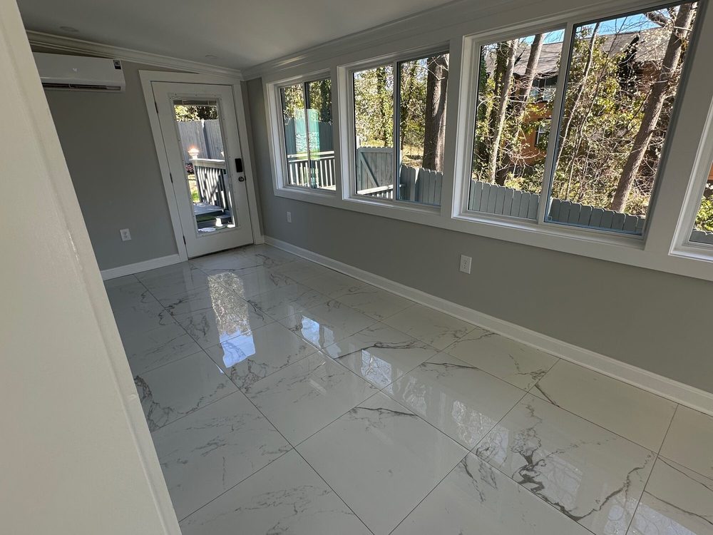 The sunroom's glass door opening out to the backyard and deck, with marble-tiled floor