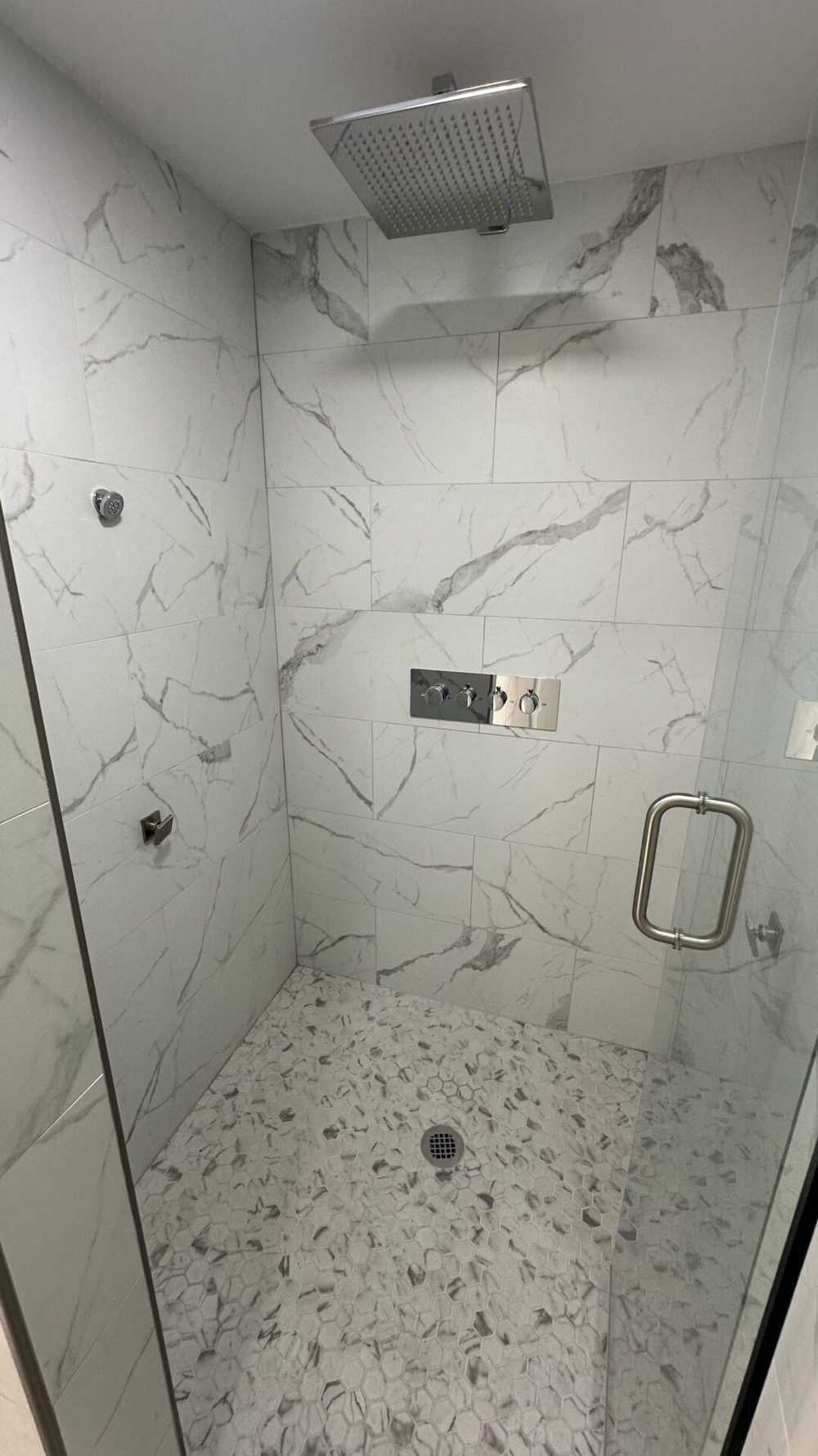 Inside the master bath's walk-in shower: full marble tile walls and a rainfall head